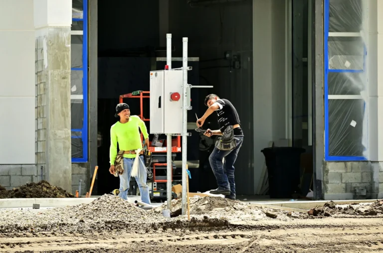 Dos técnicos instalando un gabinete de control de acceso sobre un poste