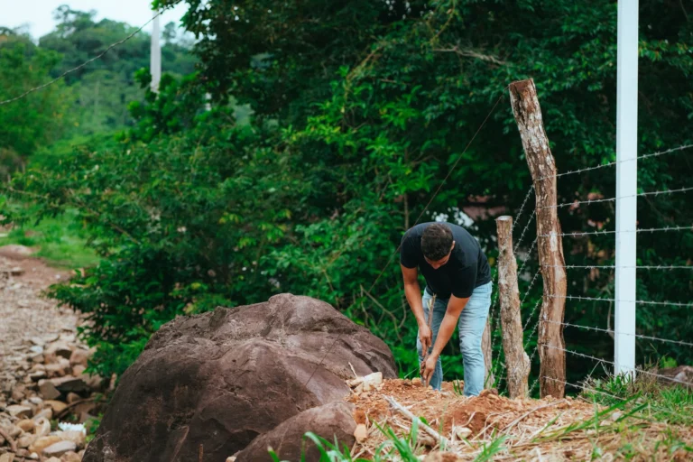 Trabajador instalando un poste para cerco de alambre en el terreno