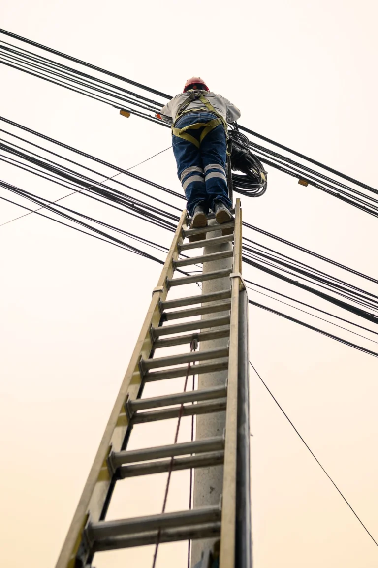 Técnico subiendo una escalera para dar mantenimiento a líneas de un cerco eléctrico