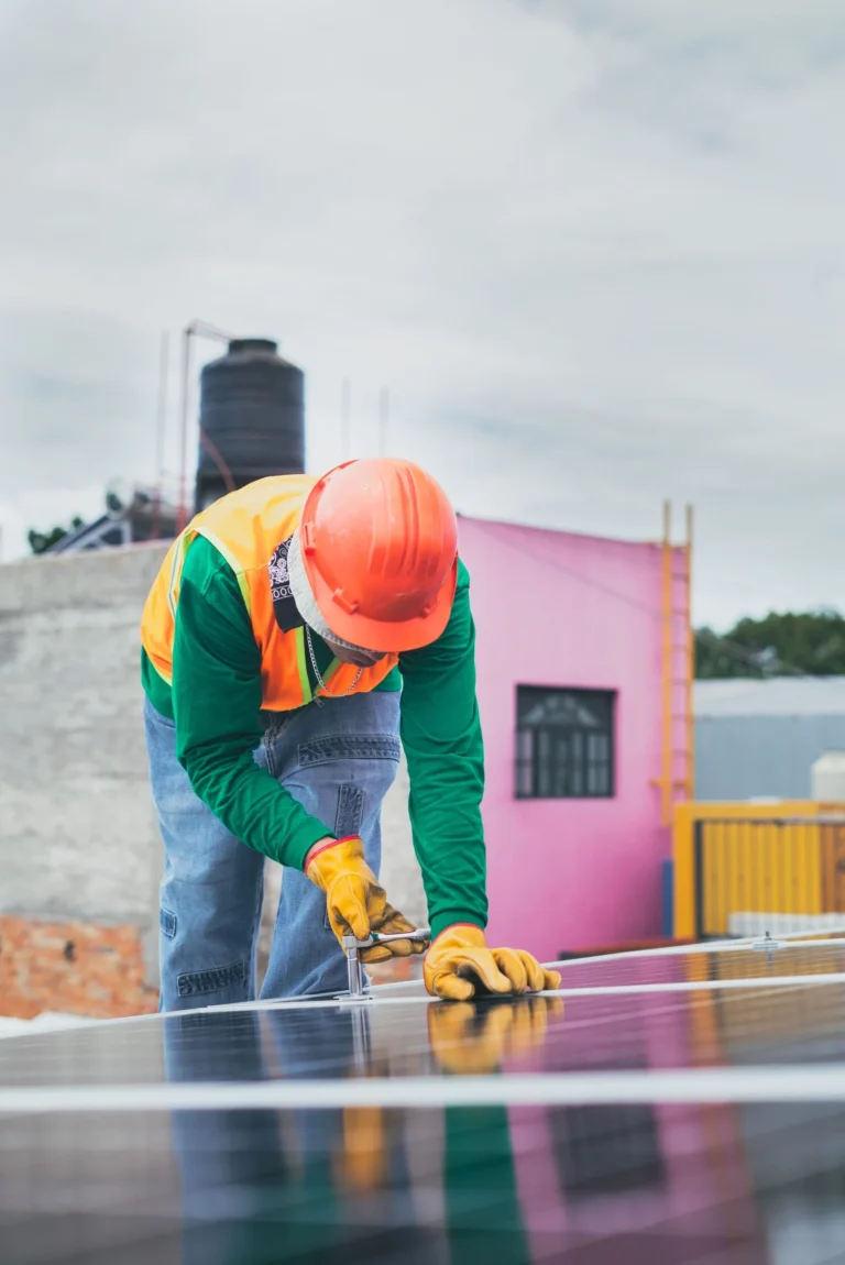 Técnico atornillando un panel solar sobre el techo de una vivienda
