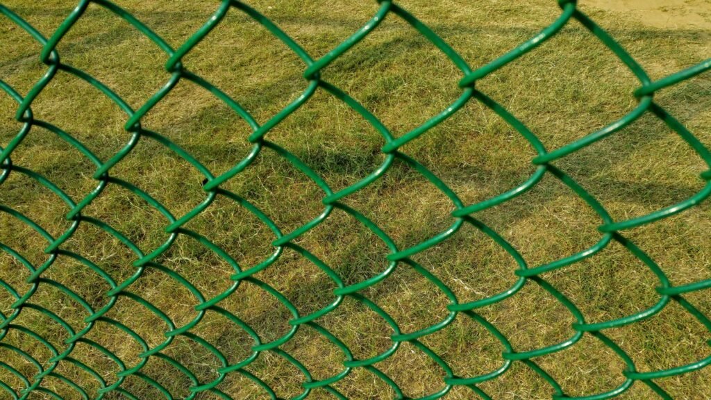 Malla ciclónica con recubrimiento verde sobre pasto
