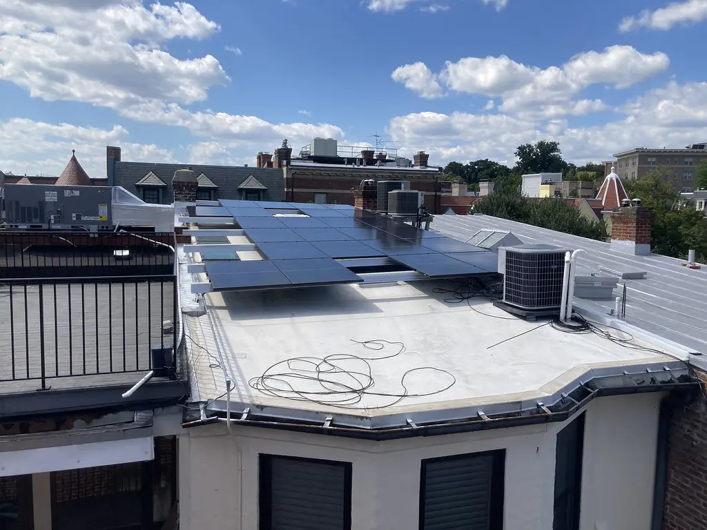 Azotea plana con paneles solares instalados junto a una unidad de aire acondicionado