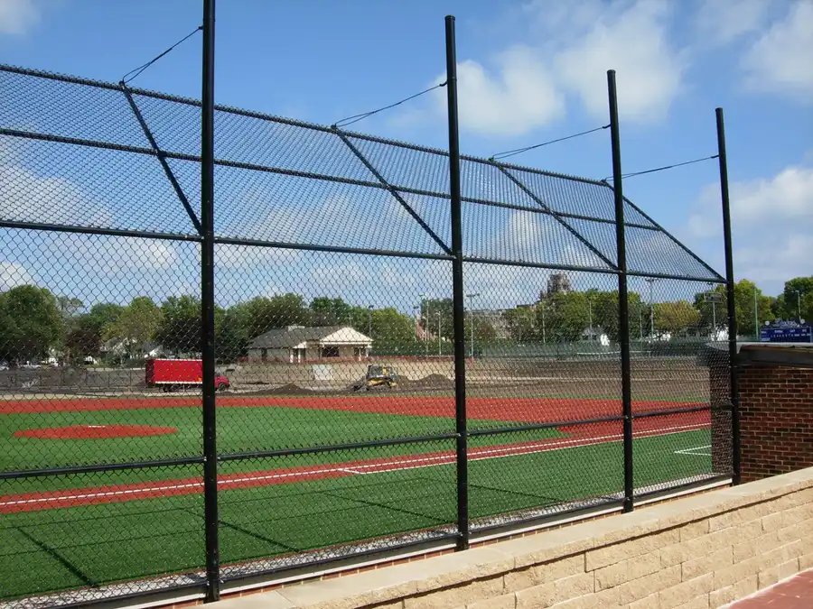 Backstop alto de malla ciclónica detrás del home en un campo de béisbol