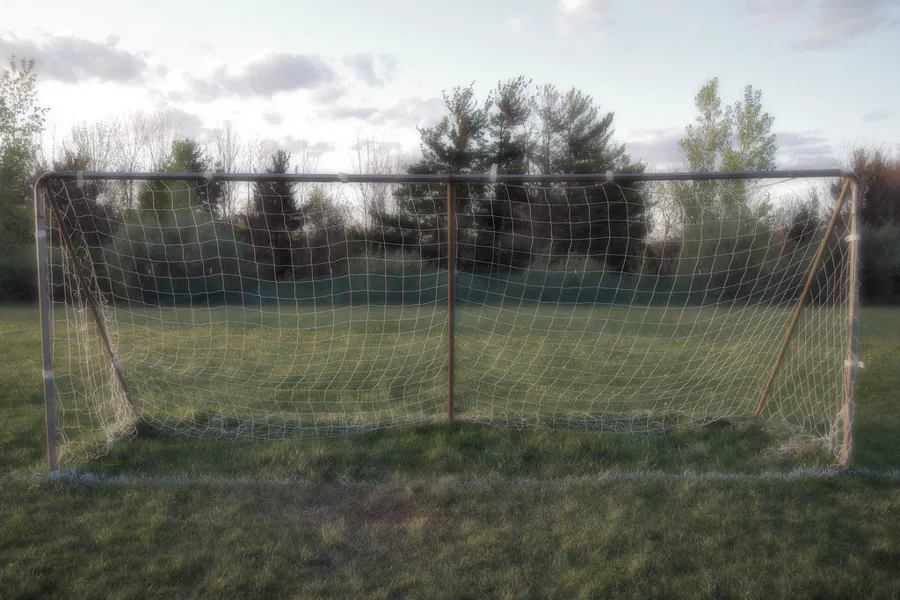 Portería de fútbol con la cerca perimetral de malla al fondo