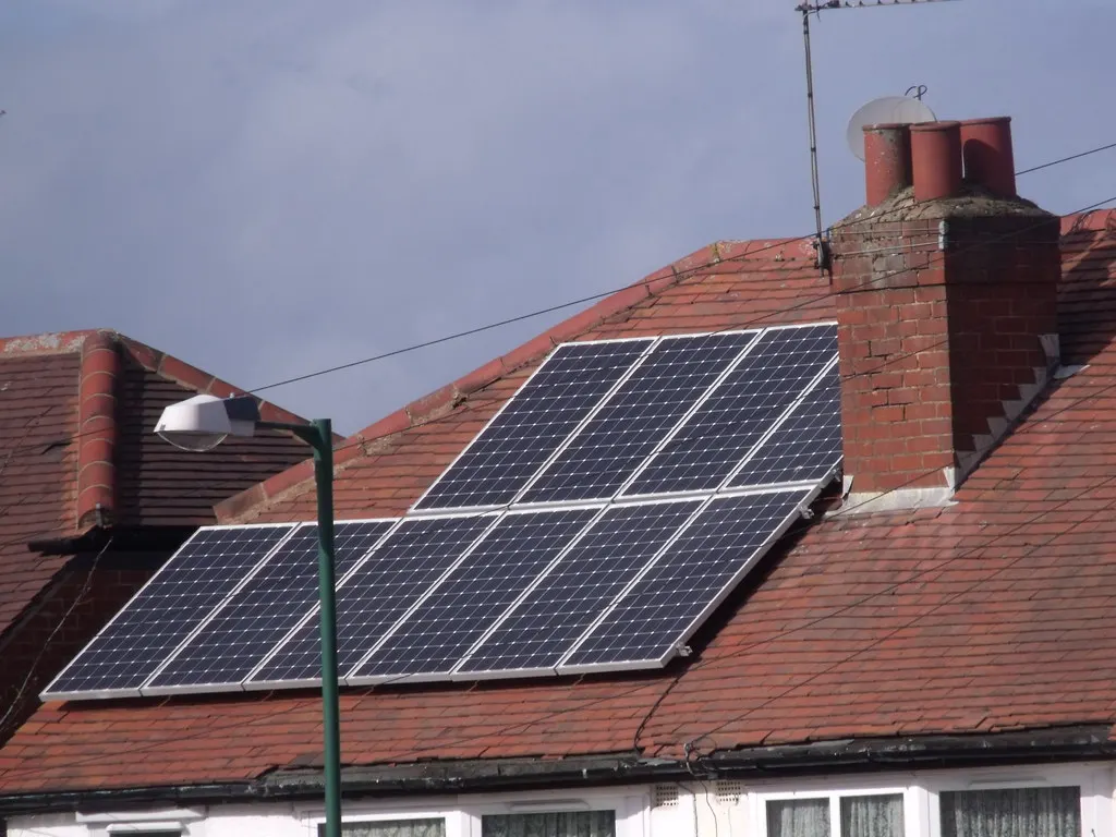 Casa con techo de teja roja y paneles solares instalados en dos niveles
