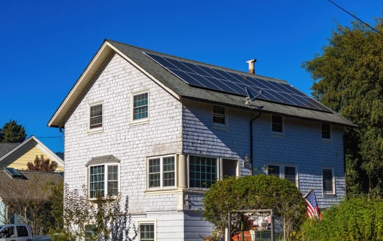 Casa de dos pisos con paneles solares instalados en el techo bajo cielo despejado