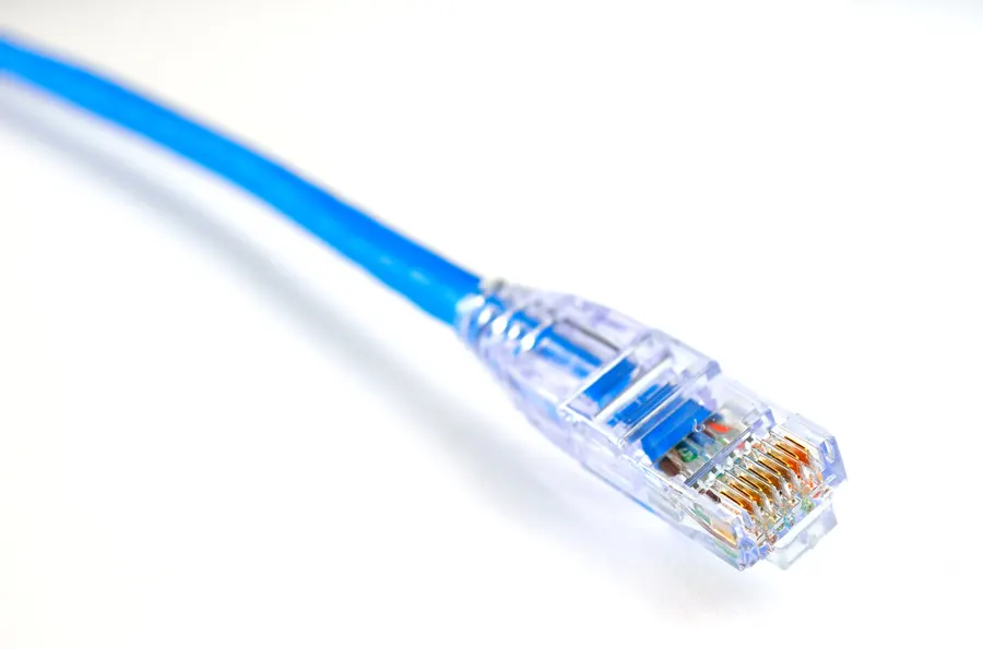 Conector RJ45 transparente en la punta de un cable UTP azul