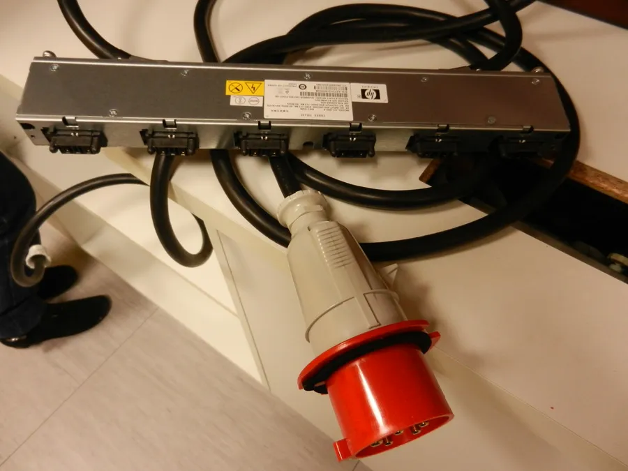 Conector trifásico industrial rojo conectado a una toma de corriente