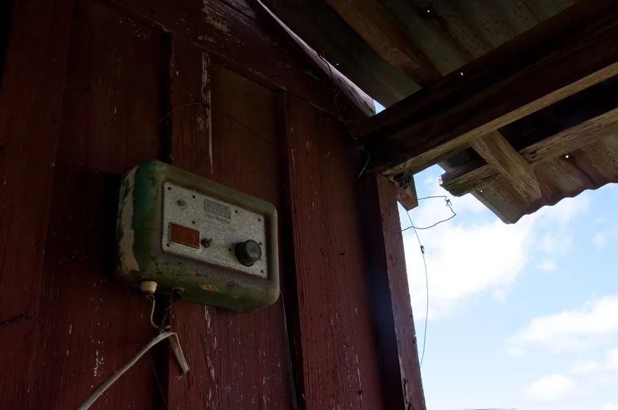 Energizador de cerco eléctrico montado en la pared de madera de un granero