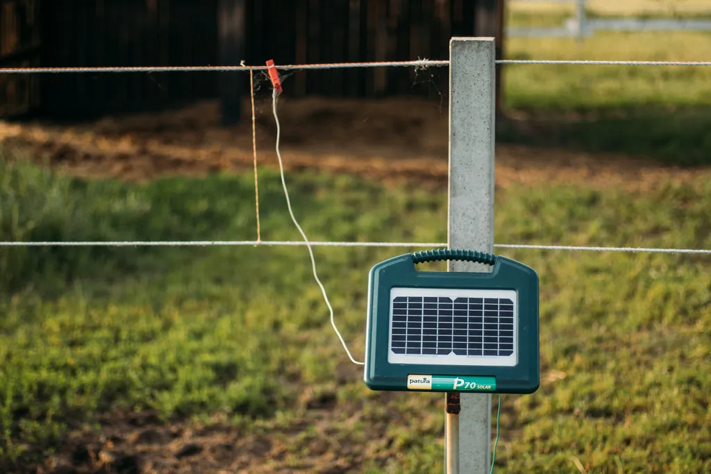 Energizador solar de cerco eléctrico montado en un poste en el campo