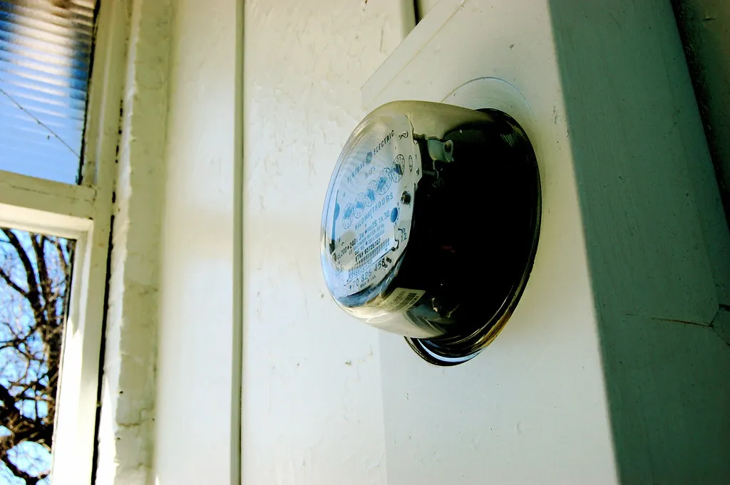 Medidor de luz redondo instalado en la pared exterior de una casa