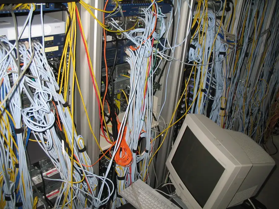 Rack de red con decenas de cables sin etiquetar enredados frente a los equipos