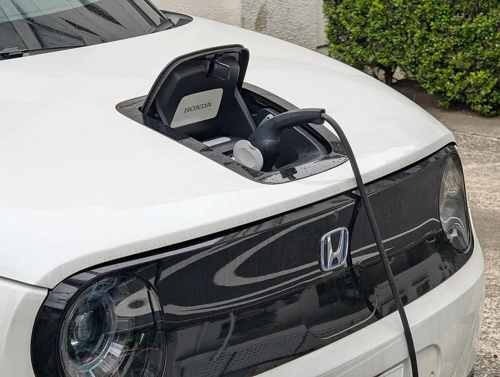 Auto eléctrico blanco cargando por el puerto de carga del cofre