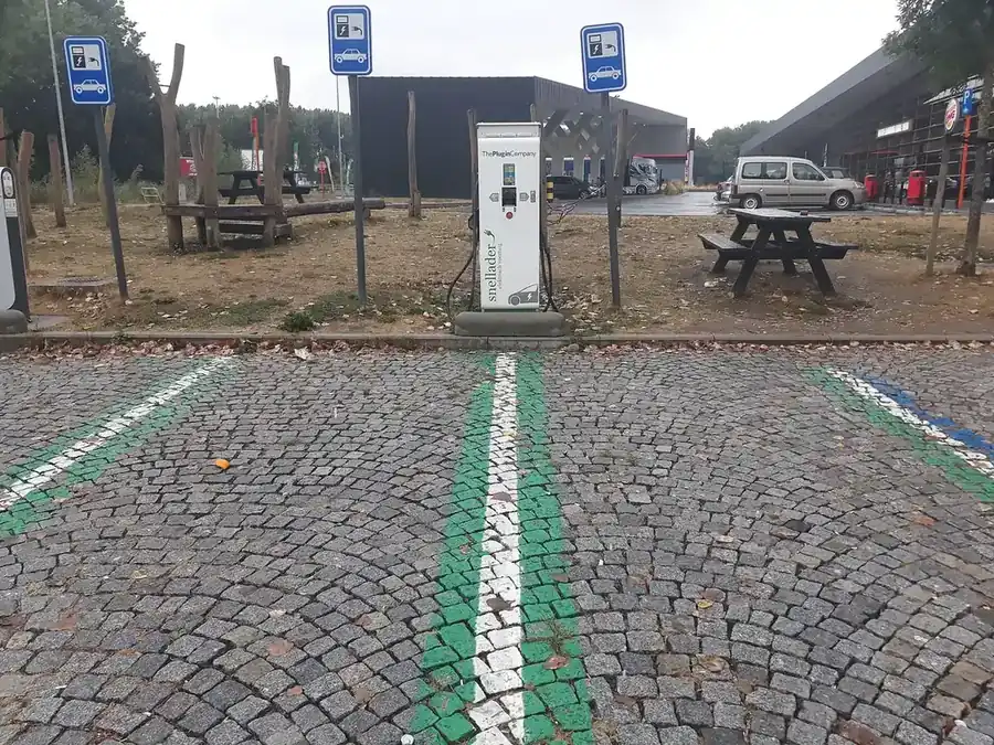 Cargador para autos eléctricos en un área de descanso con mesas, junto a la carretera