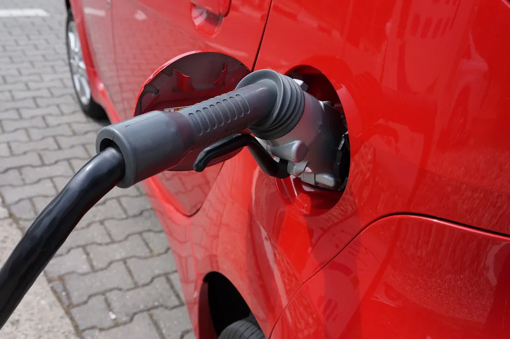 Conector de carga rápida conectado a un auto eléctrico rojo