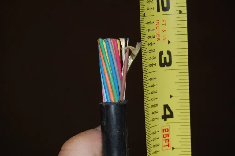 Corte de un cable de fibra óptica con sus hilos de colores junto a una cinta métrica