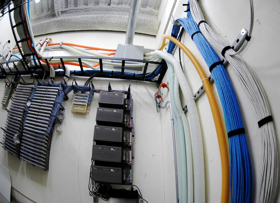 Cuarto de telecomunicaciones con charola de cable en el techo y mazos de cable ordenados con velcro