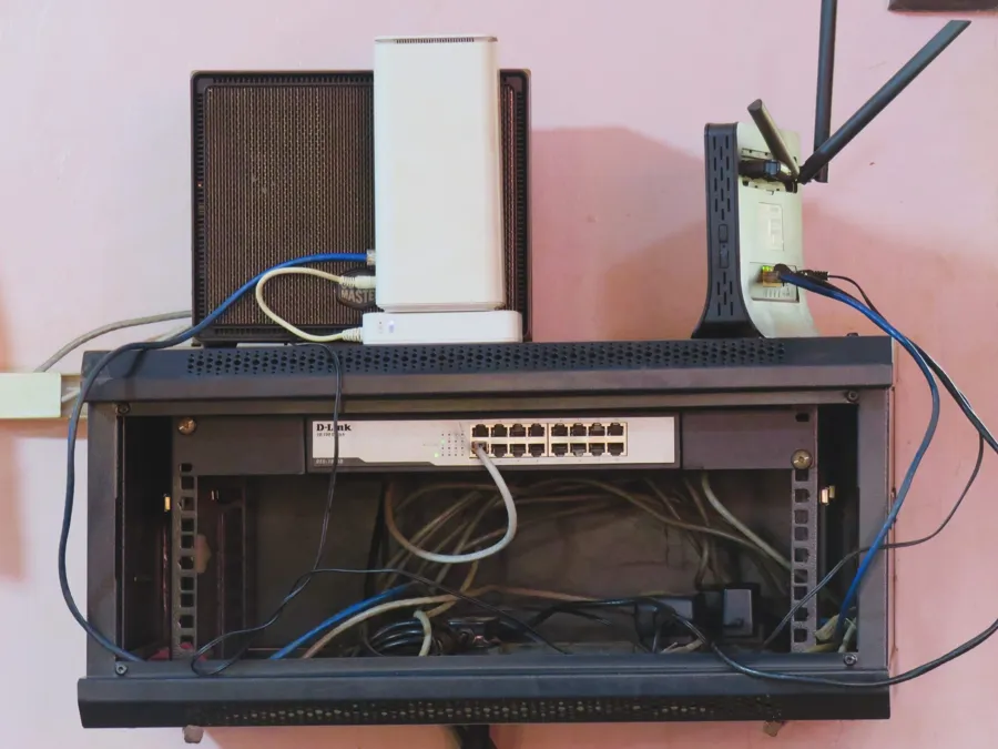 Gabinete de pared chico abierto con un switch adentro y un router encima