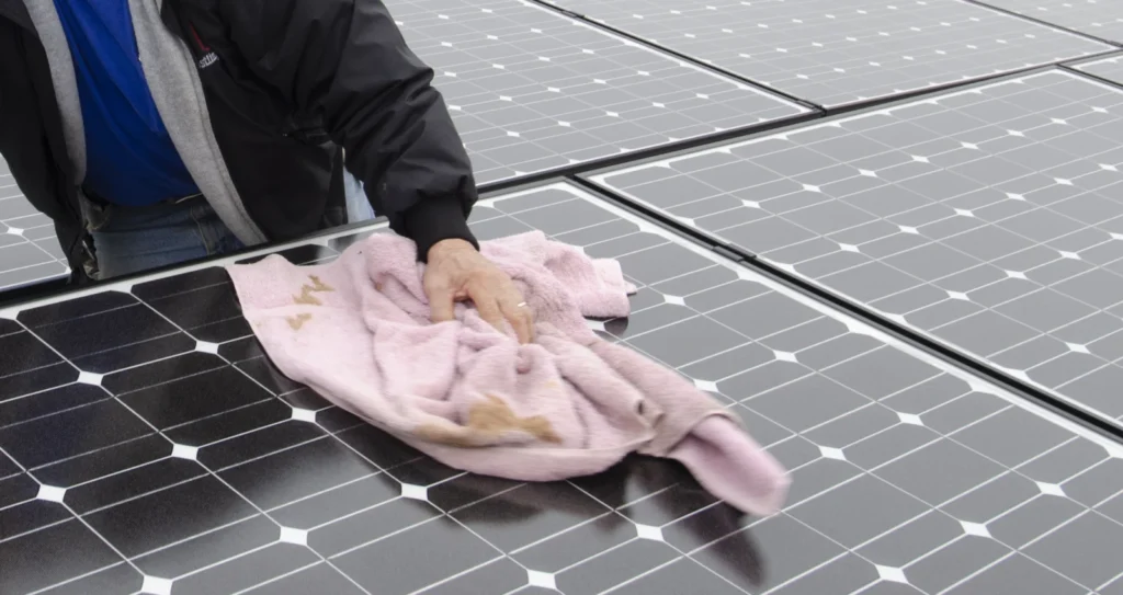 Técnico limpiando un panel solar con un paño