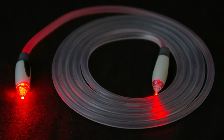 Cable de fibra óptica enrollado con luz roja saliendo por sus dos puntas