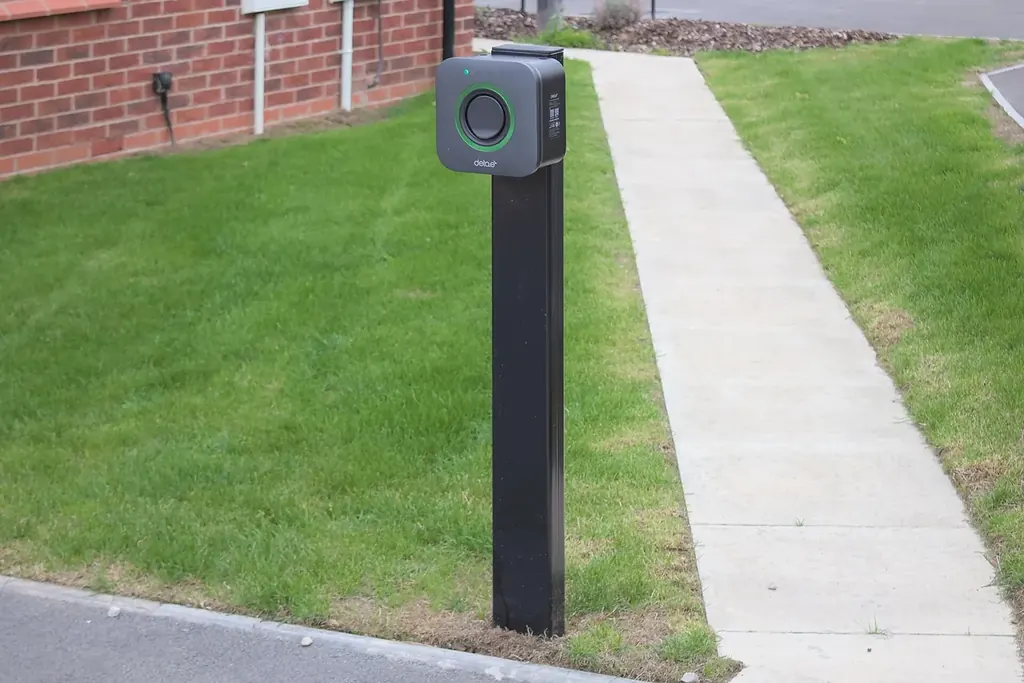 Poste de carga para autos eléctricos instalado junto al andador de un edificio de oficinas