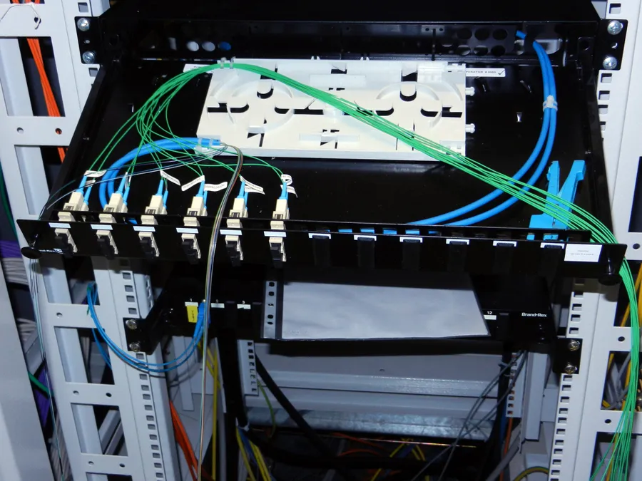 Rack de telecomunicaciones con panel de fibra óptica y cordones conectados