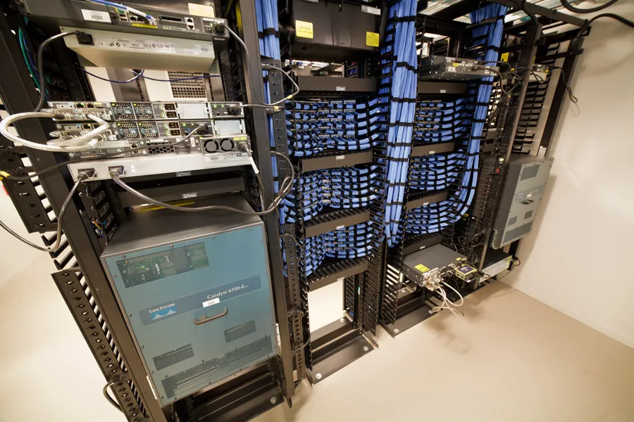 Racks abiertos de dos postes con organizadores verticales llenos de cable azul